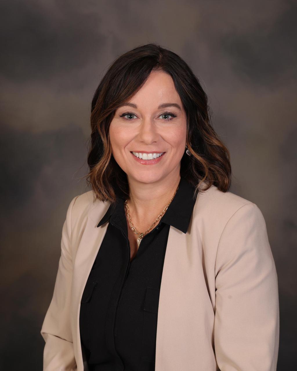 A woman with brown hair is smiling.